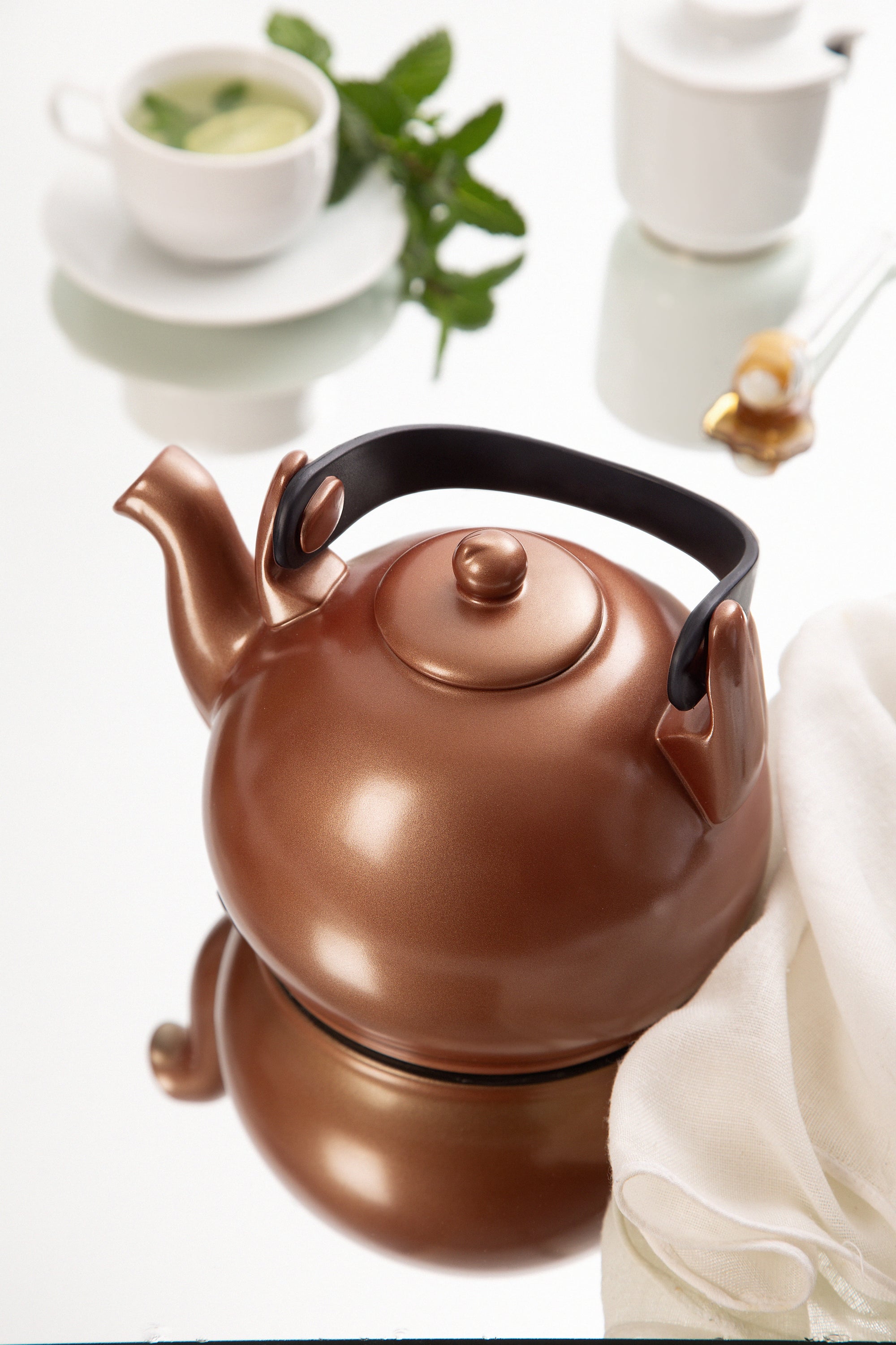 Copper-colored teapot on a white surface with a blurred background
