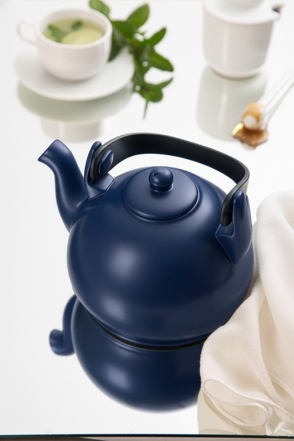 Navy blue teapot on a white surface with a blurred background